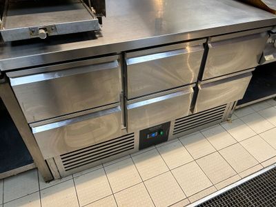 plan de travail en acier inoxydable dans une cuisine professionnelle équipée d'un four à pizza
