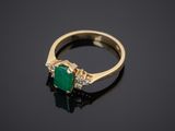 an emerald and diamond ring on a black surface