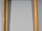 un miroir à cadre doré orné d'un motif décoratif, accroché au mur