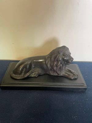 statue of a lion on a black base on a blue surface