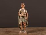 une vieille statue en bois représentant un homme tenant un chien, posée sur une table