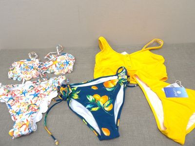 several swimsuits laid out on a couch in a room