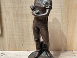 bronze statue of a boy holding a bird on a pedestal