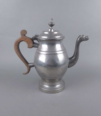 une théière ancienne en argent avec une anse en bois, sur fond gris