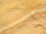 a close up picture of a bed with a yellow sheet on it