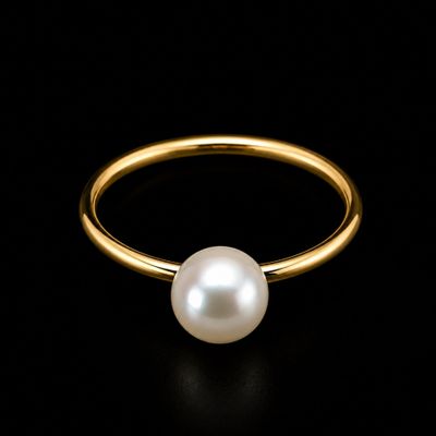a gold ring with a white pearl on a black background