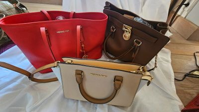 trois sacs à main de couleurs différentes posés sur un drap blanc