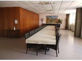 une longue table avec des chaises dans une pièce où est accroché un tableau au mur
