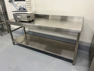 une table en acier inoxydable avec une cuisinière dans un coin