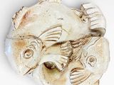 a white plate with two fish on it on a white surface