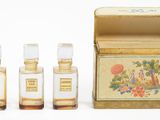 trois petits flacons de parfum posés à côté d'une boîte sur une surface blanche