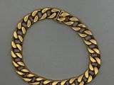 un bracelet en or avec des maillons de type « curb » sur fond gris