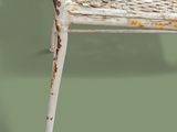 a white wicker chair that is sitting on a green surface