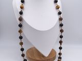 a necklace with tiger eye beads on a wooden stand