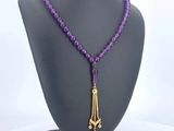 a close up of a necklace on a mannequin with purple beads