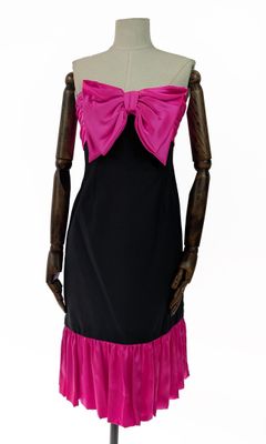 La robe est noire et rose, avec un nœud rose sur le devant.