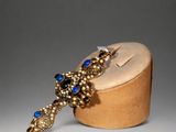 a close up of a gold and blue broochle on a wooden box