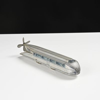 une petite maquette de train en argent posée sur une table blanche