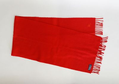 red scarf with fringes laying on a white surface
