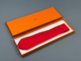 une boîte orange contenant un nœud papillon rouge, posée sur une table