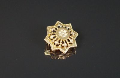 gros plan d'une broche en or sur une surface noire