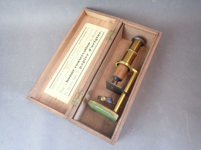 une boîte en bois contenant un microscope et une paire de ciseaux