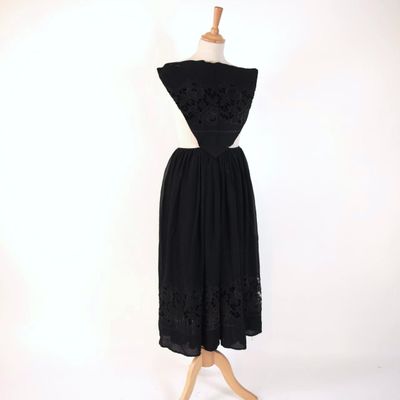 a black dress on a mannequin stand with a white background