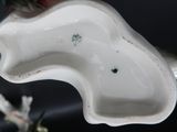 un objet en porcelaine blanche en forme de cheval, avec une fleur dans la bouche