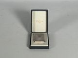 an image of a silver ring in a box on a white surface