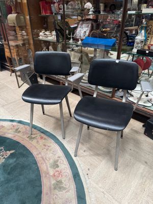 three black chairs sitting in a room with a rug on the floor