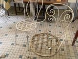 a white wrought chair sitting in a room with a table and chairs