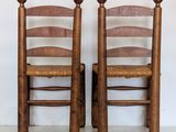 two wooden chairs sitting next to each other on a white floor