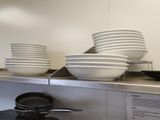 several plates and pans are stacked on a shelf in a kitchen