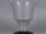 un vase en verre transparent avec un socle noir posé sur une table