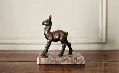 une statue en bronze représentant un cerf, posée sur un socle en marbre