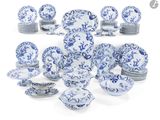 Des assiettes et des plats en porcelaine bleue et blanche sont disposés sur une surface blanche