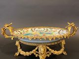 an ornate gold and blue bowl on a stand on a black surface