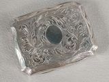 an antique silver cigarette case with a blue stone in the center