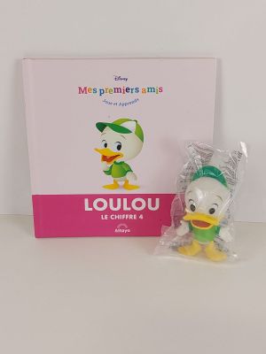 un gros plan sur un petit canard en peluche posé à côté d'un livre