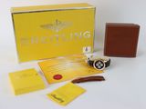 Montre Breitling avec son coffret et ses papiers, posée sur une table blanche