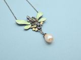 a close up of a necklace with a bee and a pearl