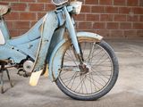 an old blue motorcycle parked in front of a brick wall