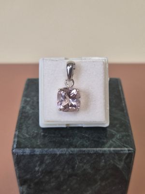 sterling silver pendant with a pink stone in a box on a marble surface
