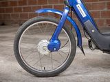 a blue motor bike parked in front of a brick wall