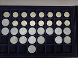 an assortment of silver coins in a black box on a table