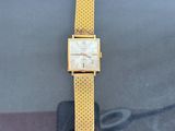 yellow gold tone watch with a mesh band