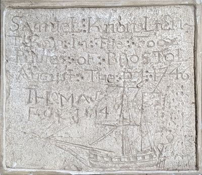 une vieille plaque en pierre représentant un navire, située devant un bâtiment