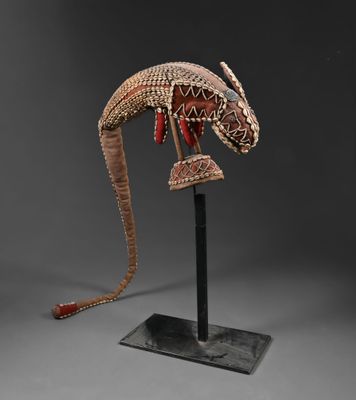 une sculpture représentant un lézard, posée sur un socle et ornée de perles rouges