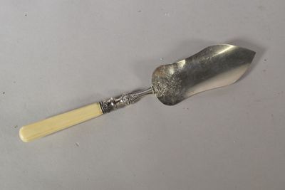 une cuillère en argent avec un manche en bois posée sur une surface blanche