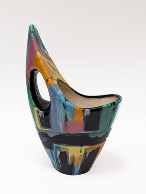 un vase coloré posé sur une surface blanche